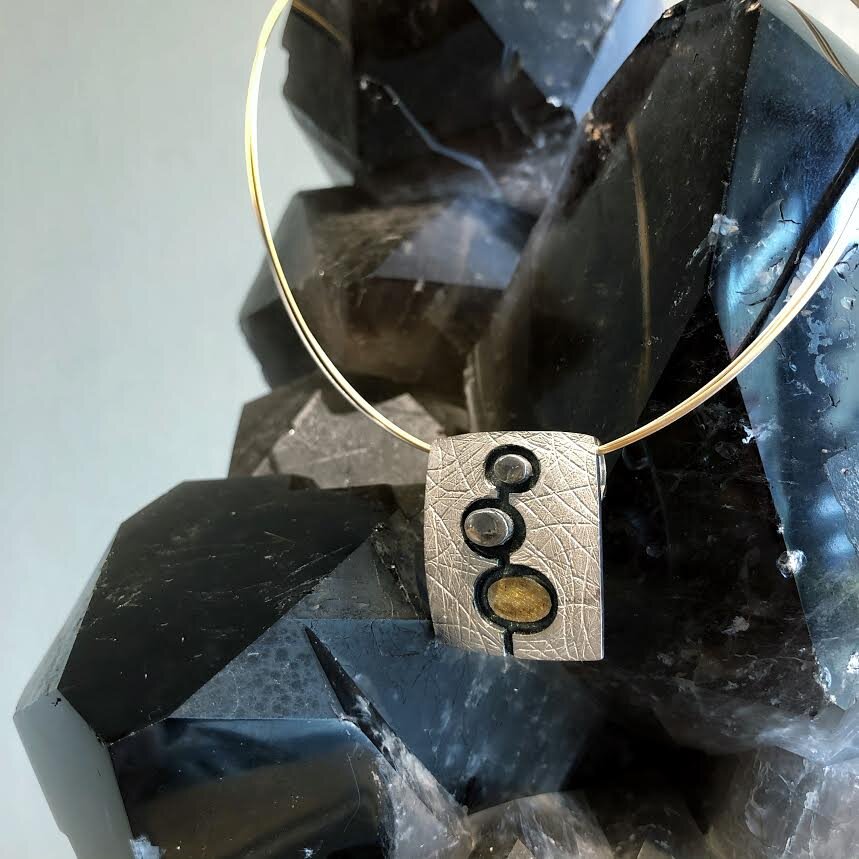 Photo of 3-D Three Circle Pendant in a decorative scene, designed by , available at Plumb Gold & Plumb Silver