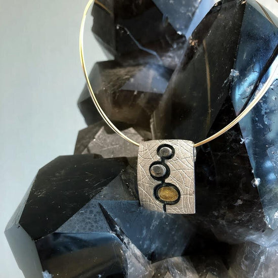 Photo of 3-D Three Circle Pendant in a decorative scene, designed by , available at Plumb Gold & Plumb Silver