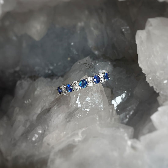 Photo of Alternating Blue Sapphire and Diamond Ring in a decorative scene, designed by , available at Plumb Gold & Plumb Silver