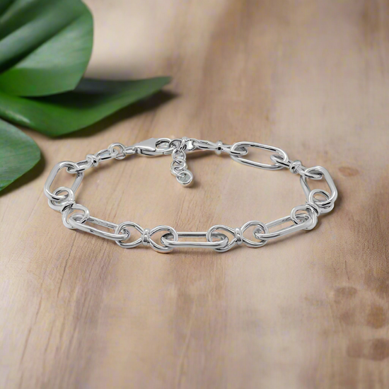 Photo of Alternating Oval and Infinity Link Bracelet in a decorative scene, designed by , available at Plumb Gold & Plumb Silver