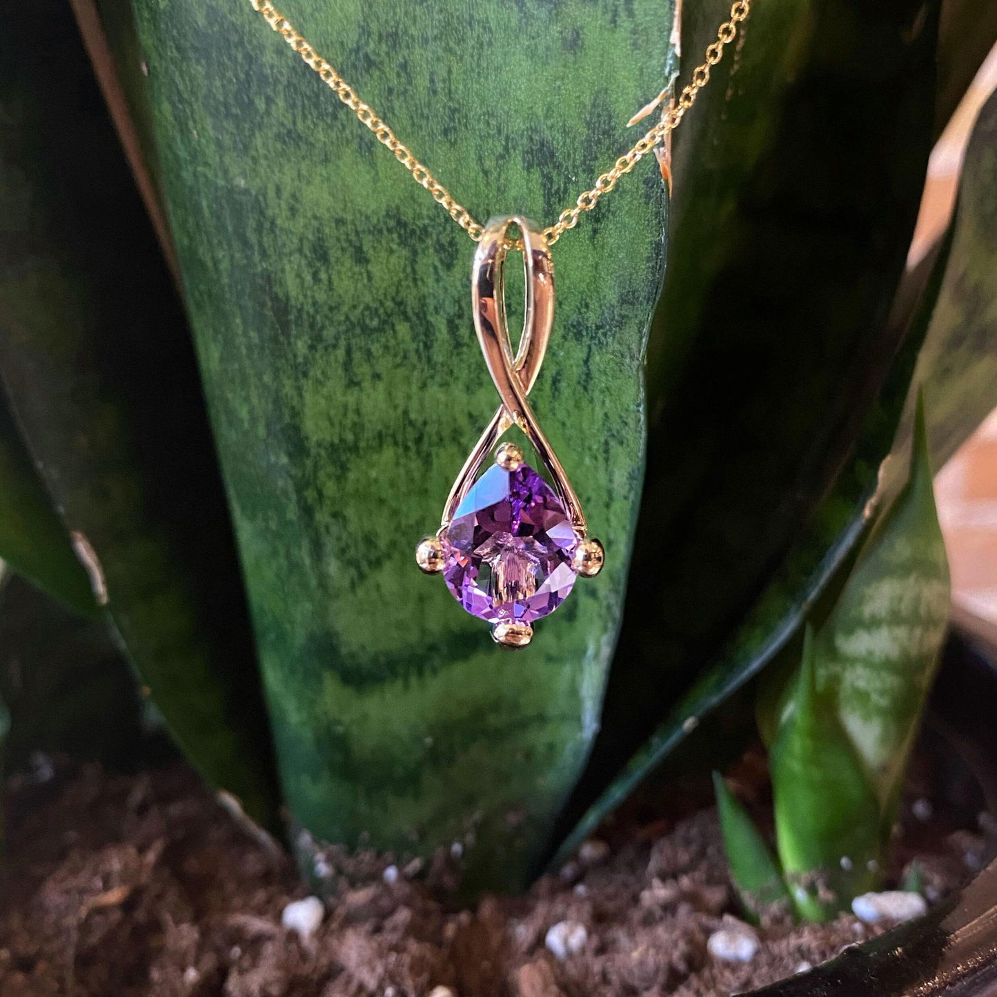Photo of Amethyst Loop Pendant in a decorative scene, designed by , available at Plumb Gold & Plumb Silver