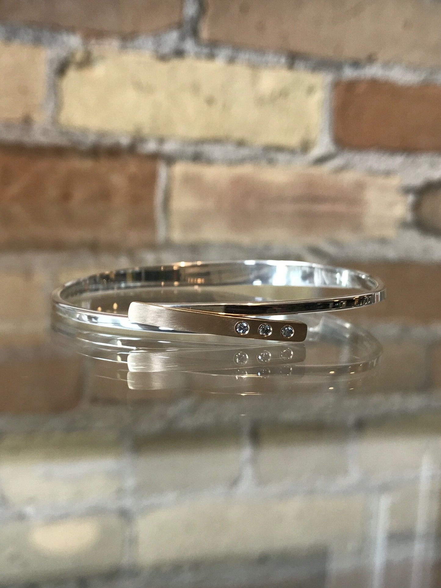 Photo of "Anticipation" Bangle in a decorative scene, designed by , available at Plumb Gold & Plumb Silver