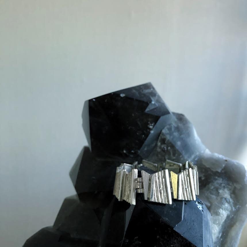 Photo of Bamboo Rhombus Bracelet in a decorative scene, designed by , available at Plumb Gold & Plumb Silver