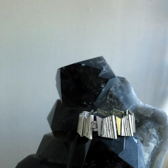 Photo of Bamboo Rhombus Bracelet in a decorative scene, designed by , available at Plumb Gold & Plumb Silver