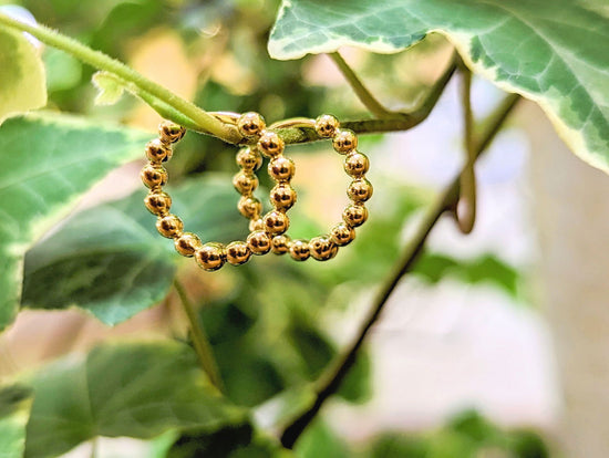 Photo of Bead Hinged Hoops in a decorative scene, designed by , available at Plumb Gold & Plumb Silver