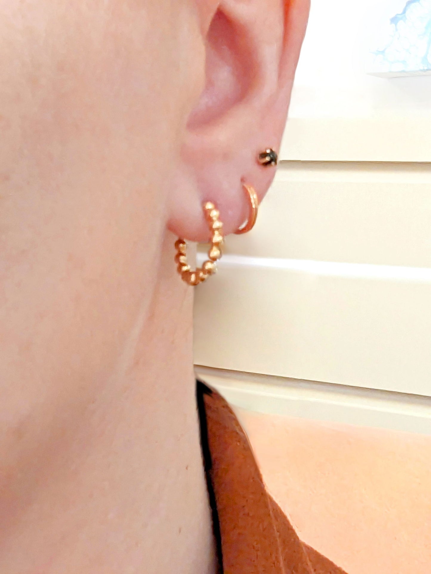 Photo of Bead Hinged Hoops in a decorative scene, designed by , available at Plumb Gold & Plumb Silver