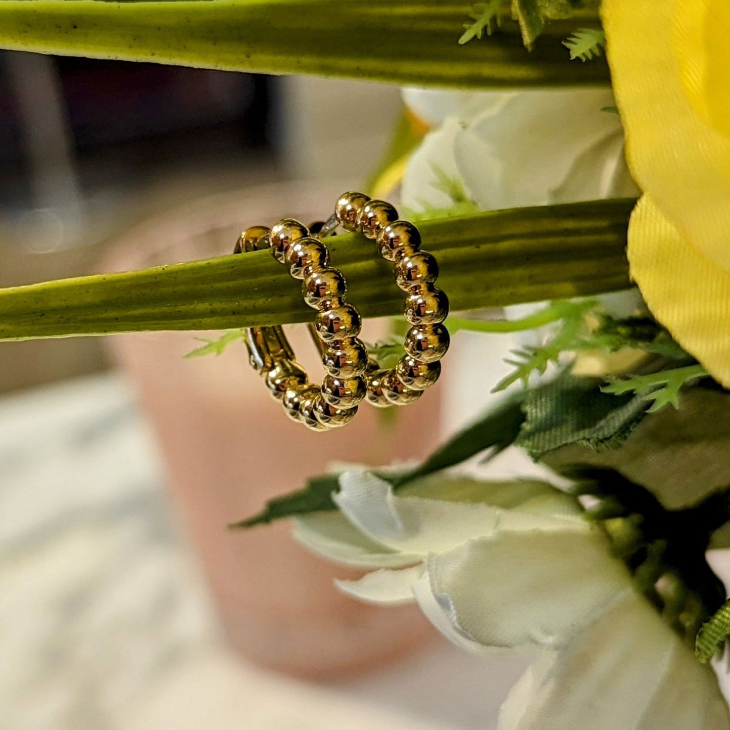 Photo of Beaded Hoop Earrings in a decorative scene, designed by , available at Plumb Gold & Plumb Silver