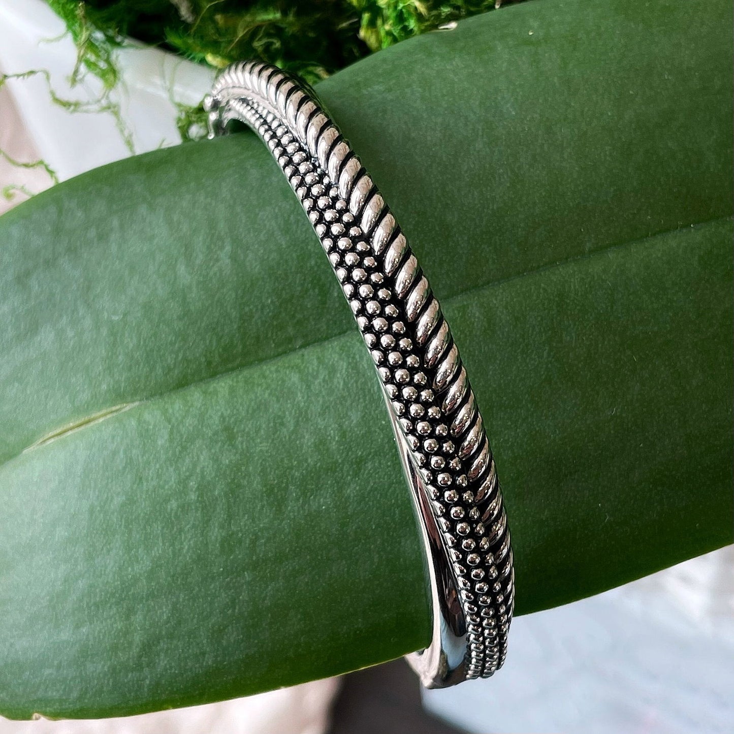 Photo of Beaded Rope Bangle in a decorative scene, designed by , available at Plumb Gold & Plumb Silver