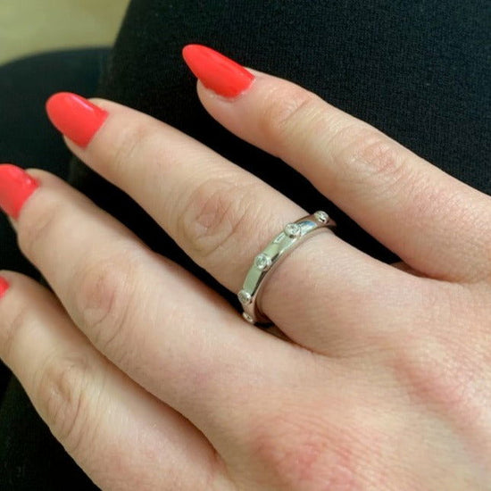 Photo of Bezel Station Stackable Ring in a decorative scene, designed by , available at Plumb Gold & Plumb Silver