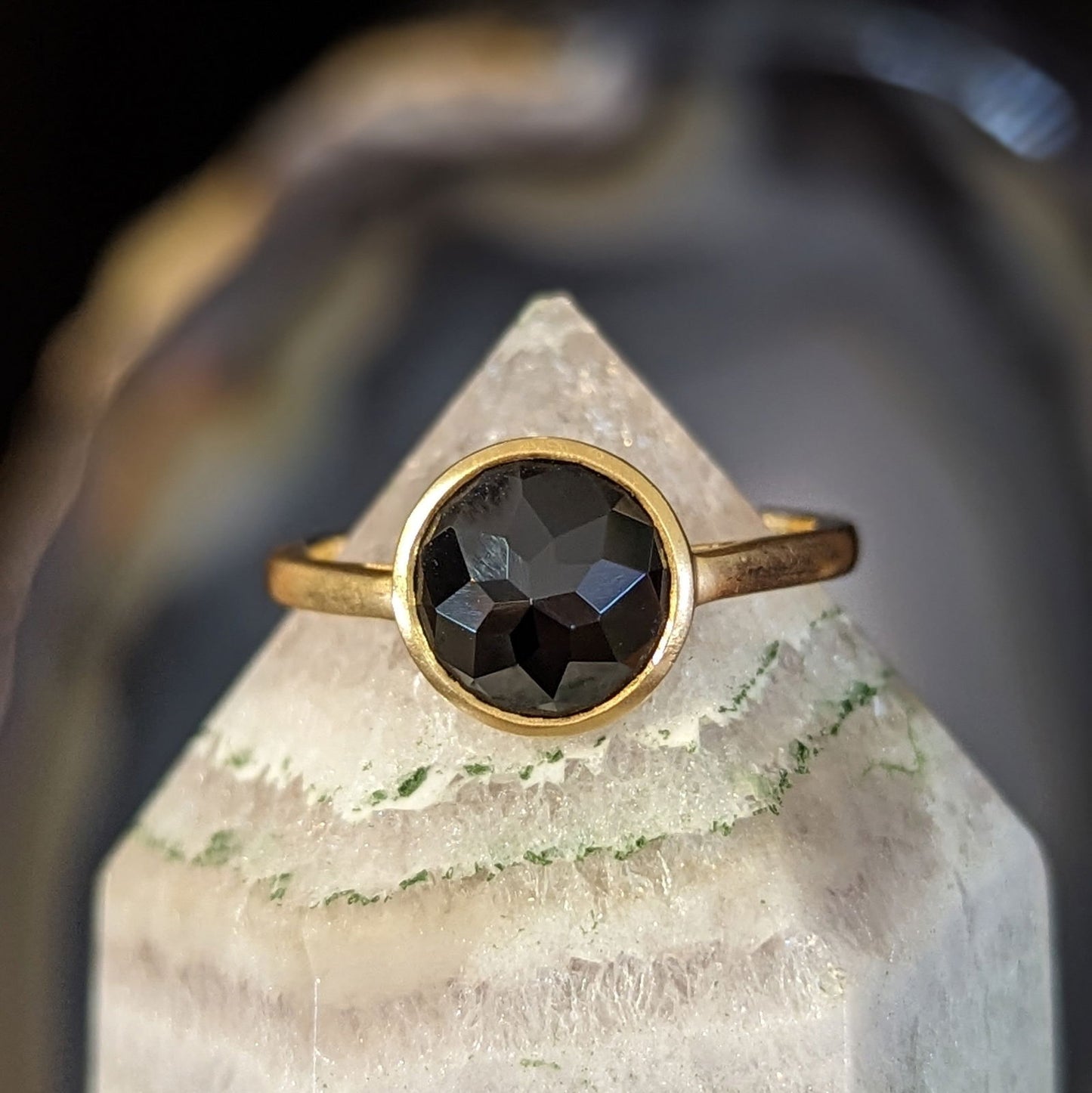 Photo of Black Spinel Stackable Ring in a decorative scene, designed by , available at Plumb Gold & Plumb Silver