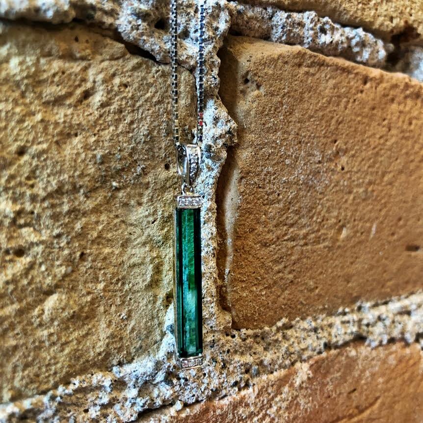 Photo of Blue-Green Tourmaline Bar Pendant in a decorative scene, designed by , available at Plumb Gold & Plumb Silver