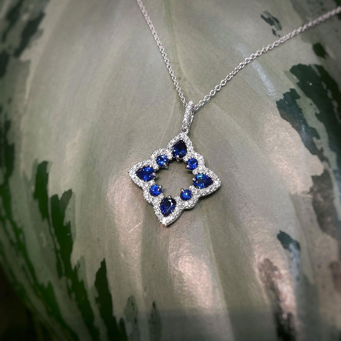 Photo of Blue Sapphire Open Shape Necklace in a decorative scene, designed by , available at Plumb Gold & Plumb Silver