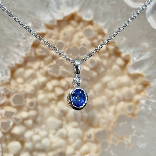 Photo of Blue Sapphire and Diamond Pendant in a decorative scene, designed by , available at Plumb Gold & Plumb Silver