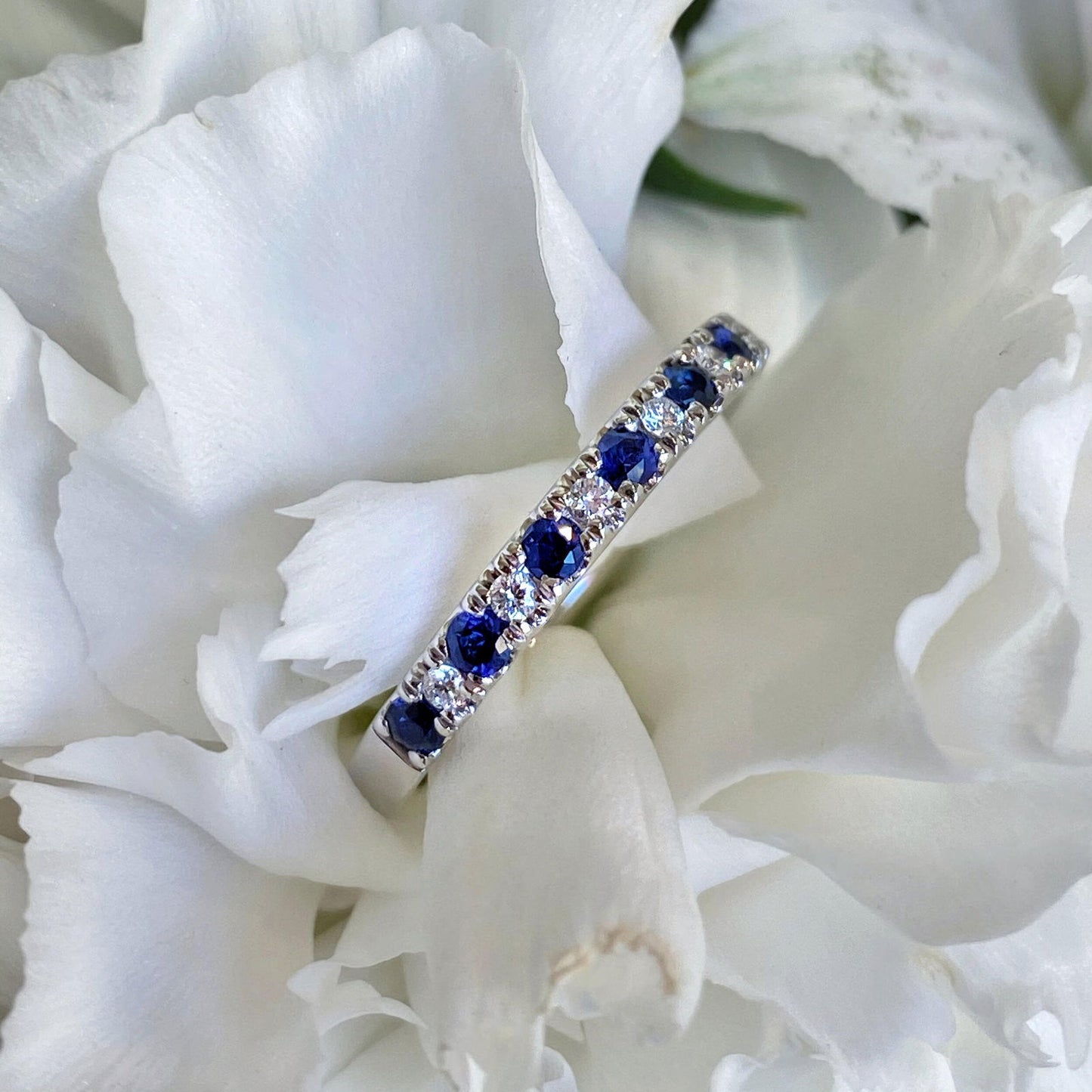 Photo of Blue Sapphire and diamond Ring in a decorative scene, designed by , available at Plumb Gold & Plumb Silver