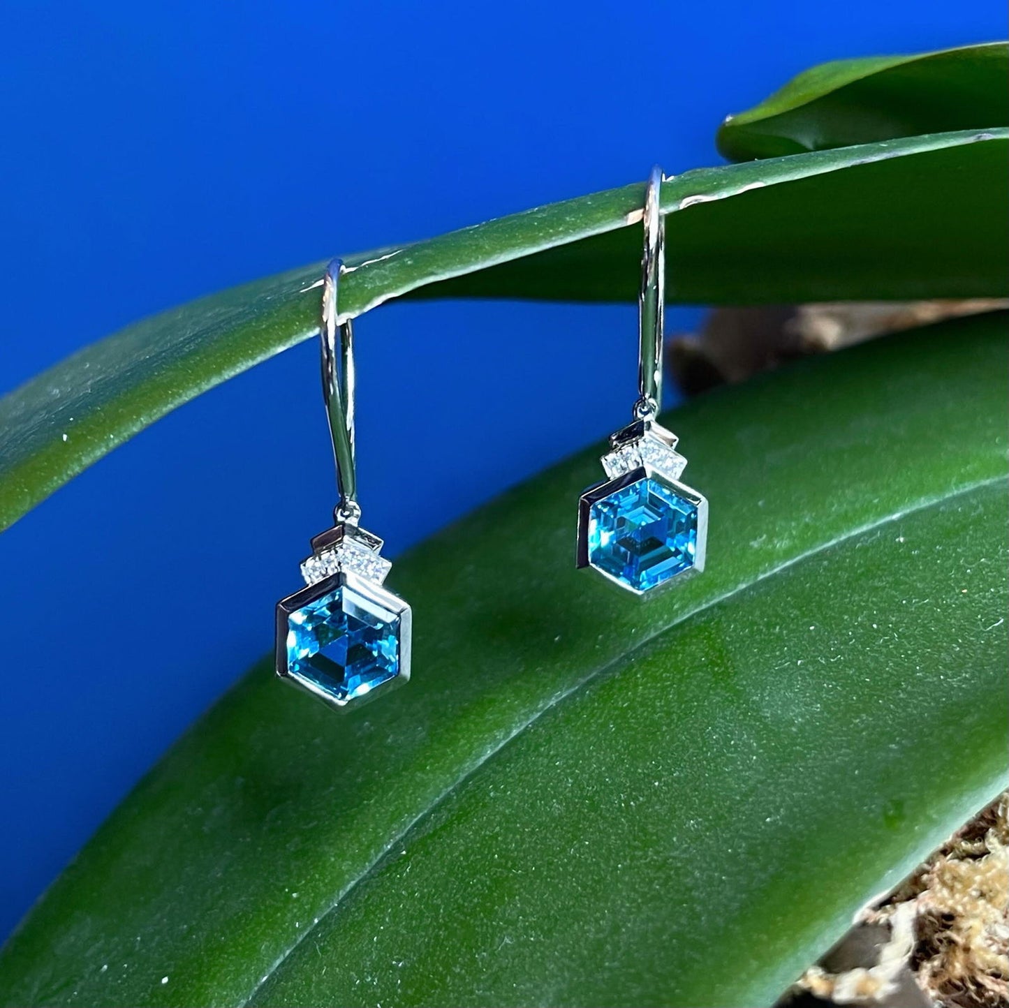 Photo of Blue Topaz Diamond Dangles in a decorative scene, designed by , available at Plumb Gold & Plumb Silver