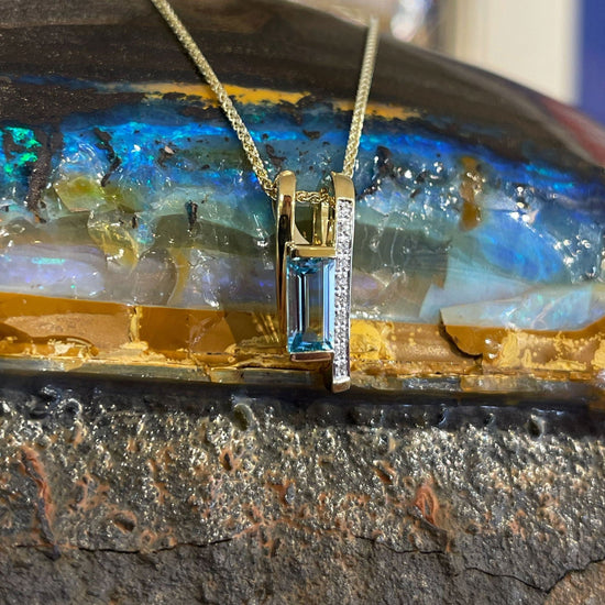 Photo of Blue Topaz and Diamond Pendant in a decorative scene, designed by , available at Plumb Gold & Plumb Silver