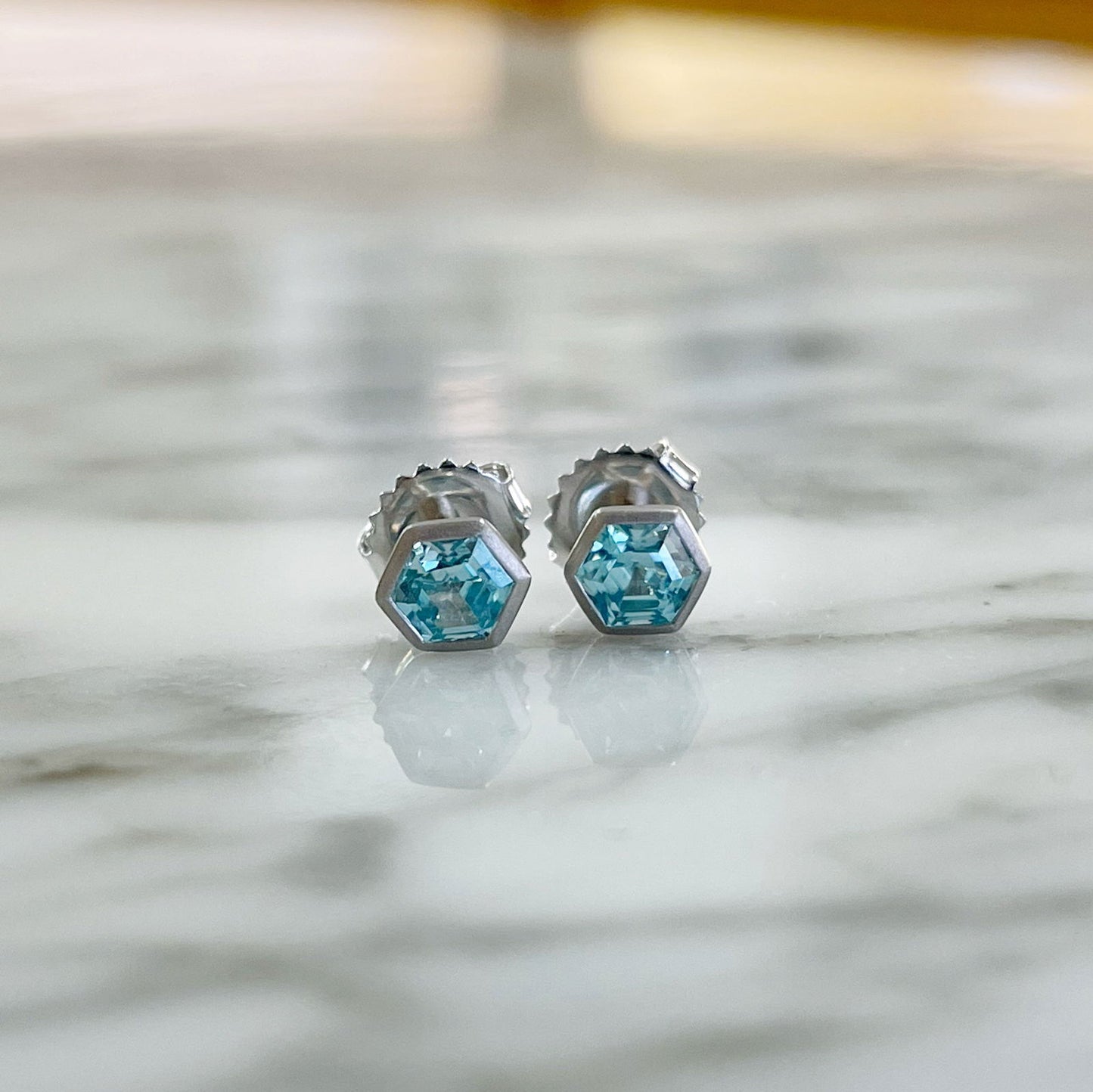 Photo of Blue Zircon Hexagon Studs in a decorative scene, designed by , available at Plumb Gold & Plumb Silver