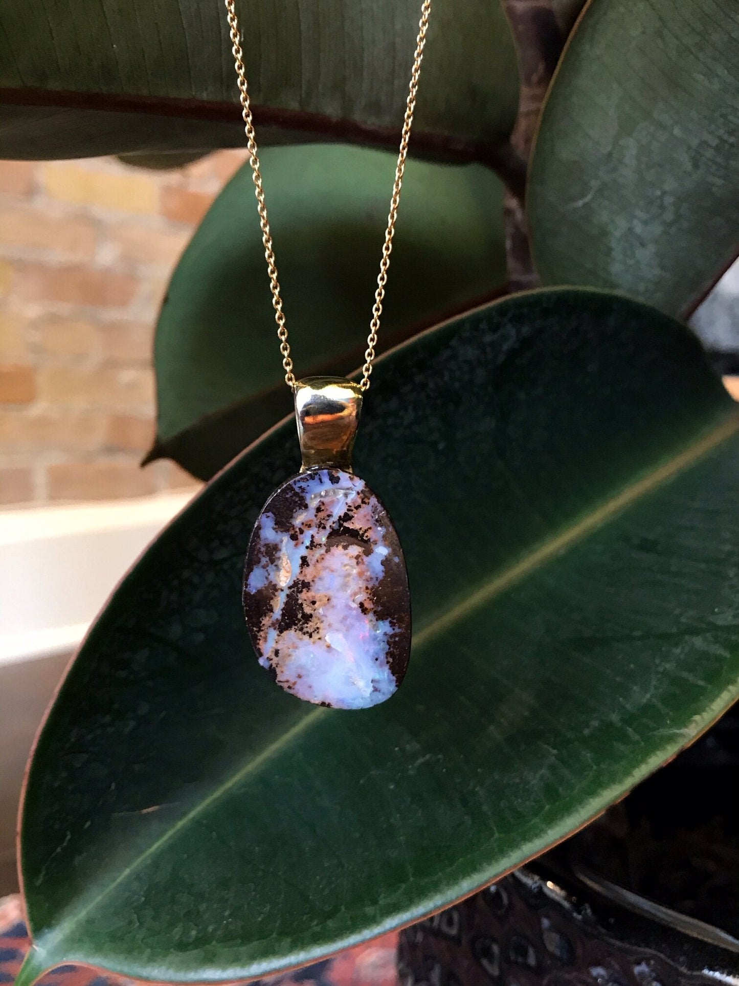 Photo of Boulder Opal Pendant in a decorative scene, designed by , available at Plumb Gold & Plumb Silver