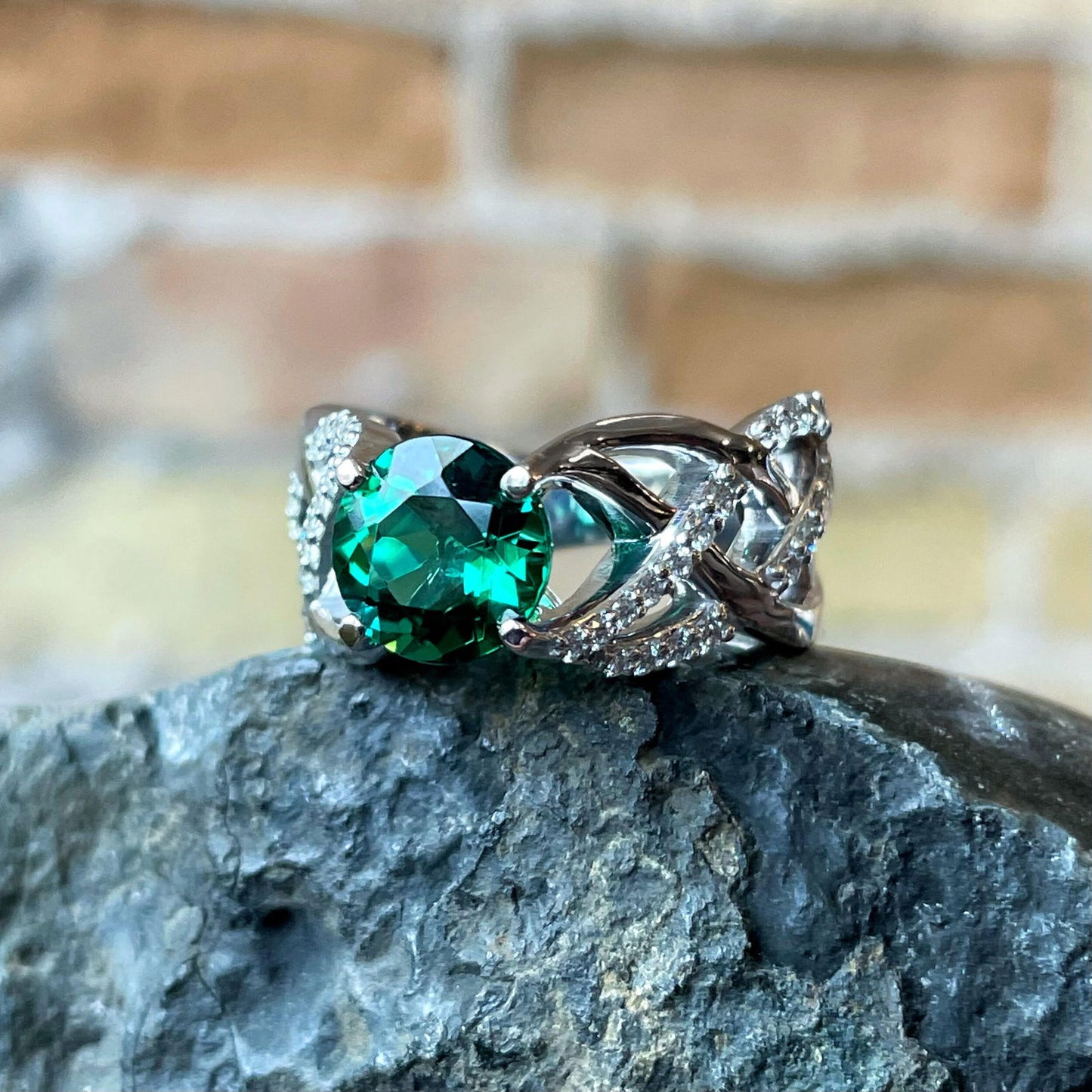 Photo of Braided Green Tourmaline Ring in a decorative scene, designed by , available at Plumb Gold & Plumb Silver