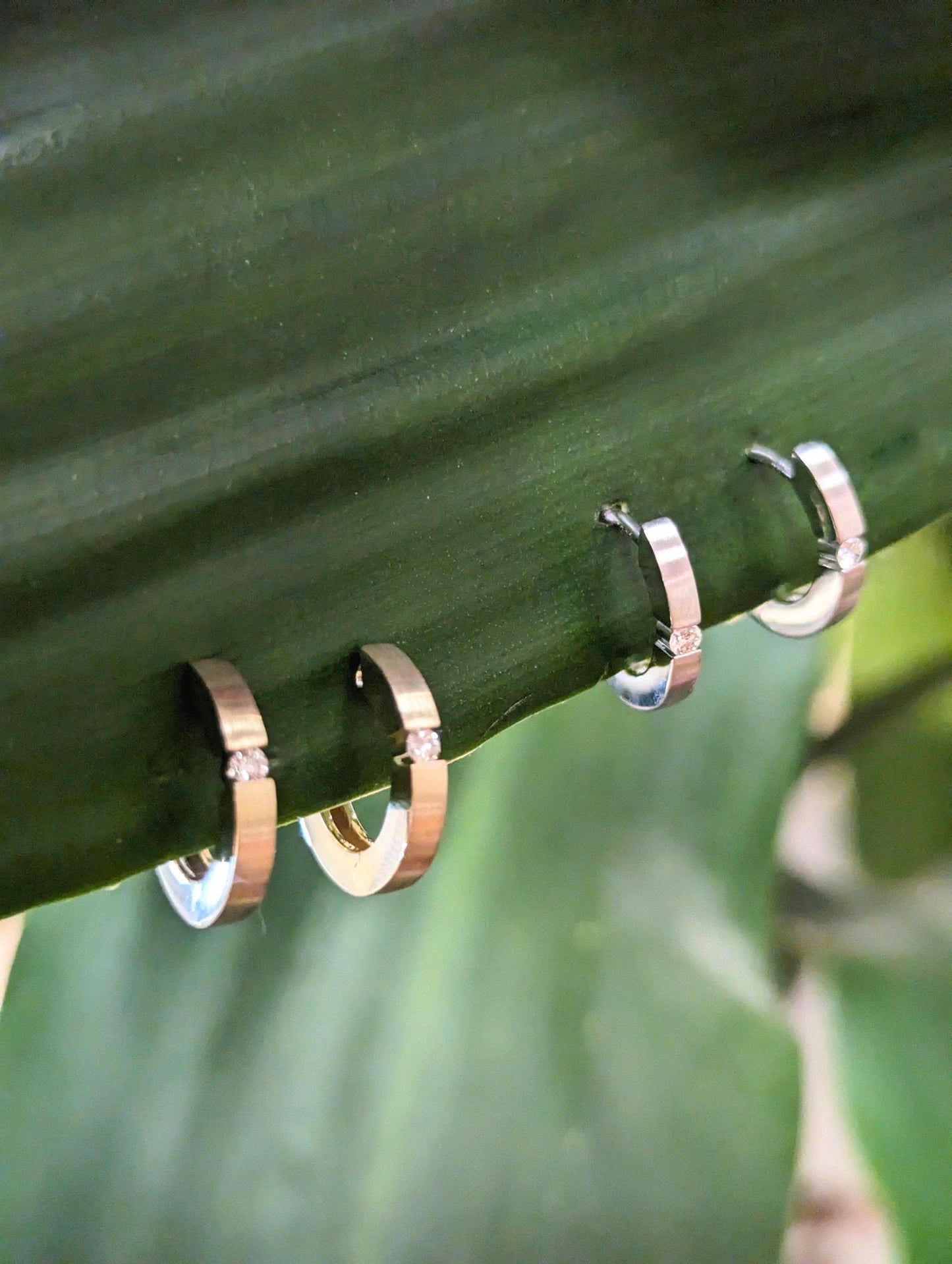 Photo of Breuning Matte Diamond Huggie Hoops in a decorative scene, designed by , available at Plumb Gold & Plumb Silver