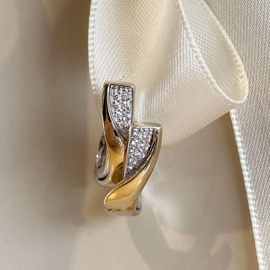 Photo of Breuning Wide Curve Huggie Earring in a decorative scene, designed by , available at Plumb Gold & Plumb Silver