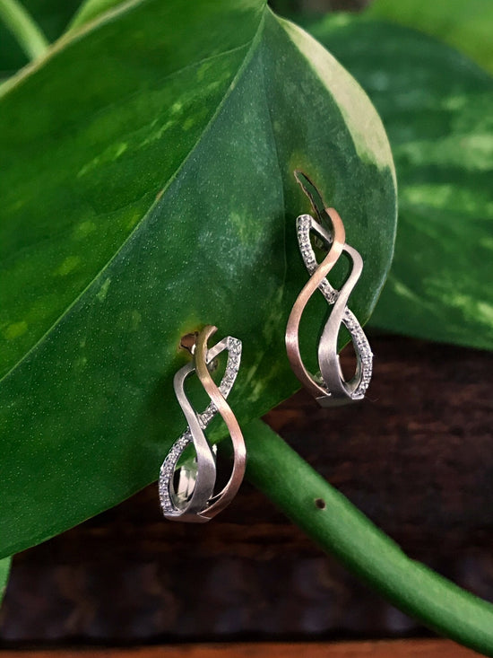 Photo of Breuning Woven Twist Diamond Earrings in a decorative scene, designed by , available at Plumb Gold & Plumb Silver