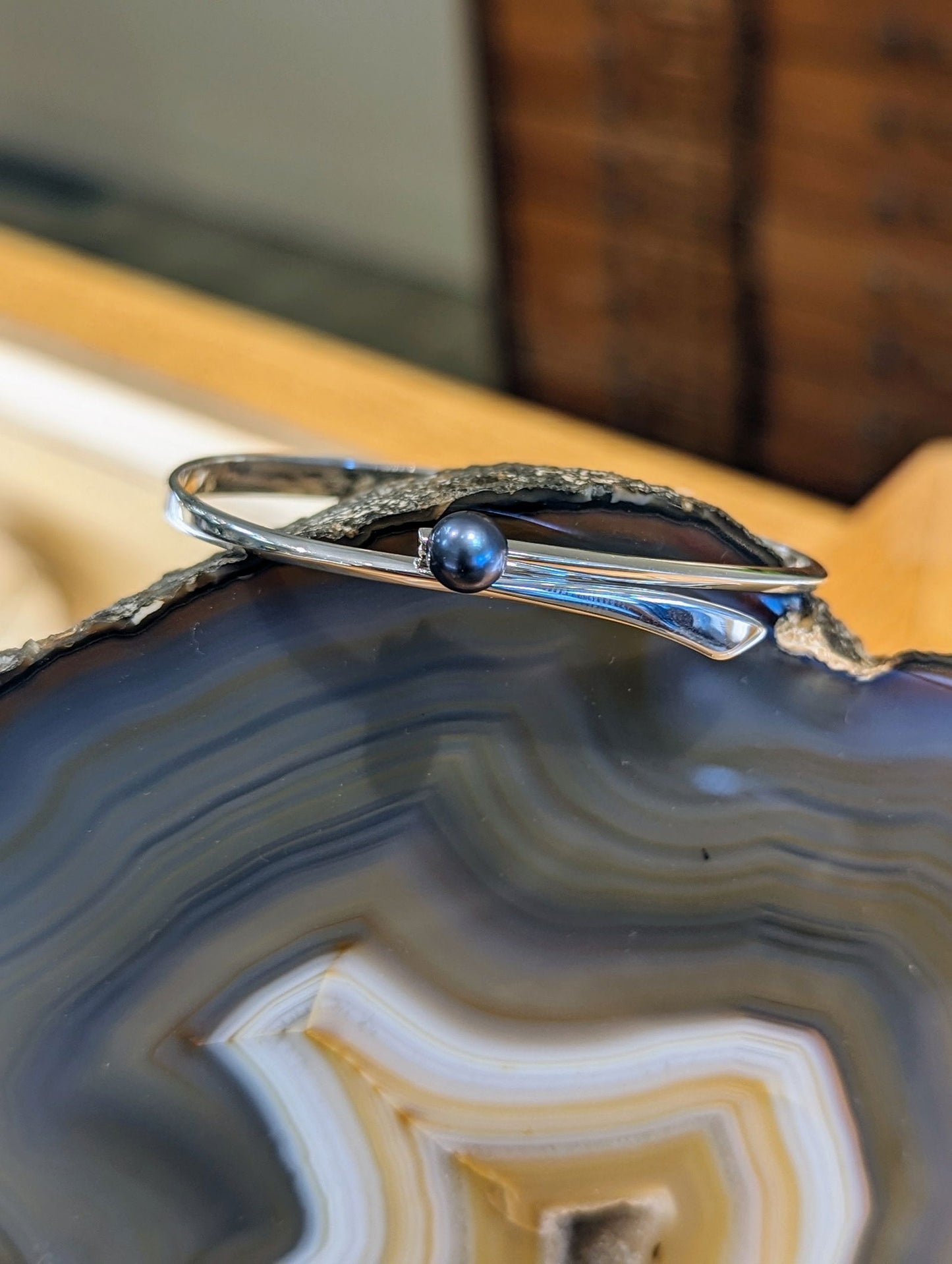 Photo of "Button" Swing Bracelet in a decorative scene, designed by , available at Plumb Gold & Plumb Silver