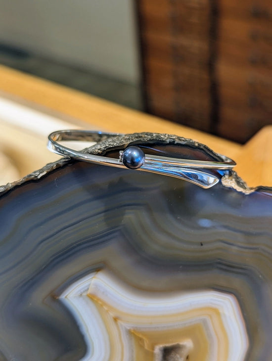 Photo of "Button" Swing Bracelet in a decorative scene, designed by , available at Plumb Gold & Plumb Silver