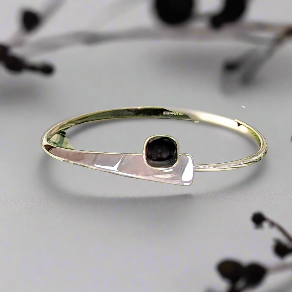 Photo of "Camber" Onyx Bracelet in a decorative scene, designed by , available at Plumb Gold & Plumb Silver
