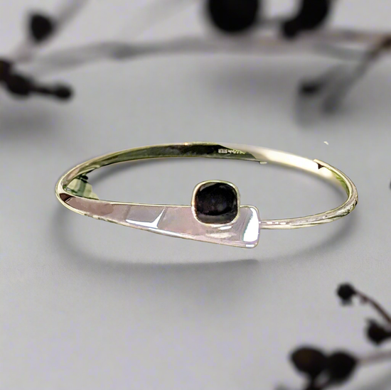 Photo of "Camber" Onyx Bracelet in a decorative scene, designed by , available at Plumb Gold & Plumb Silver