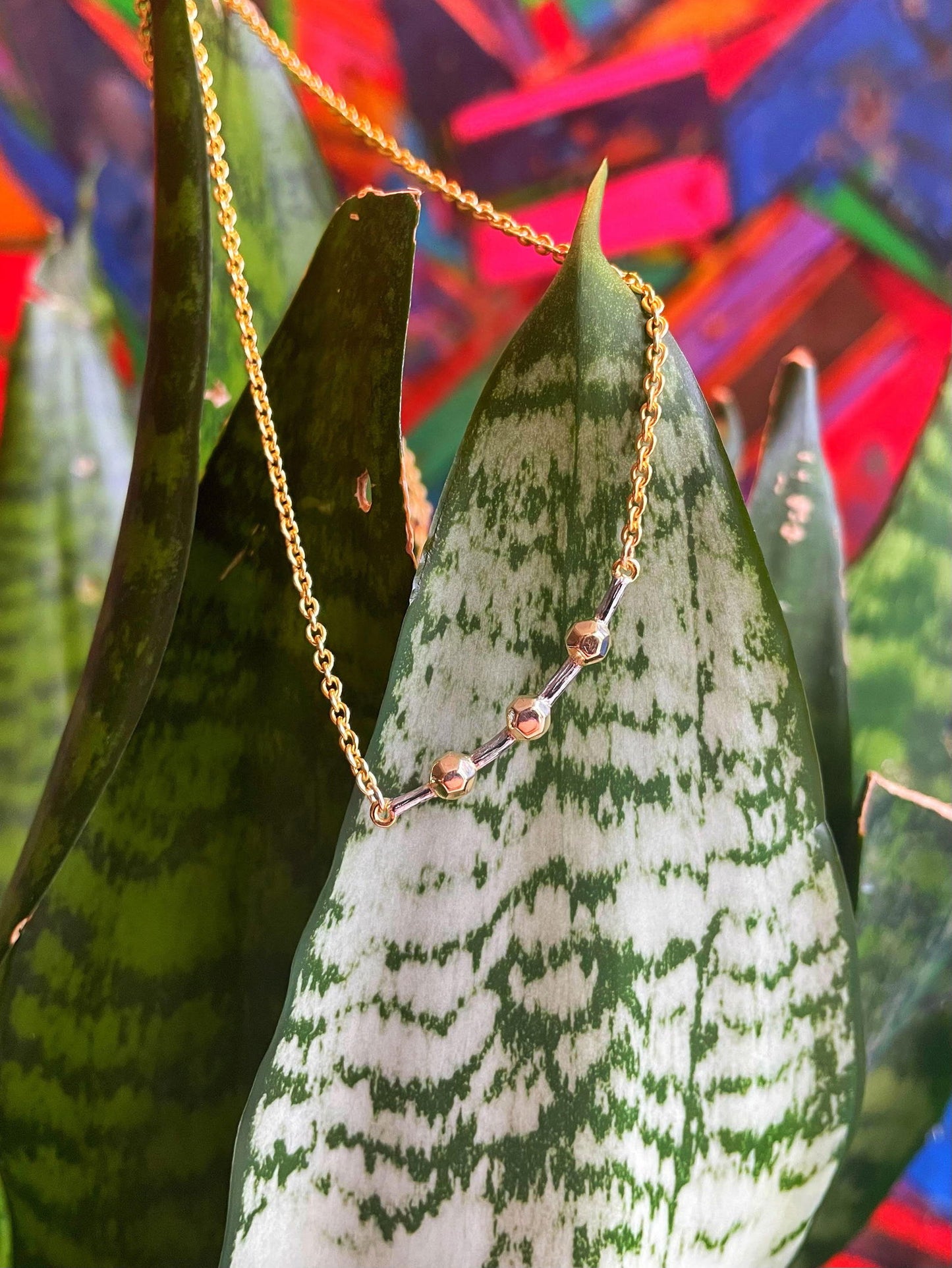 Photo of "Celestial" Smile Necklace in a decorative scene, designed by , available at Plumb Gold & Plumb Silver