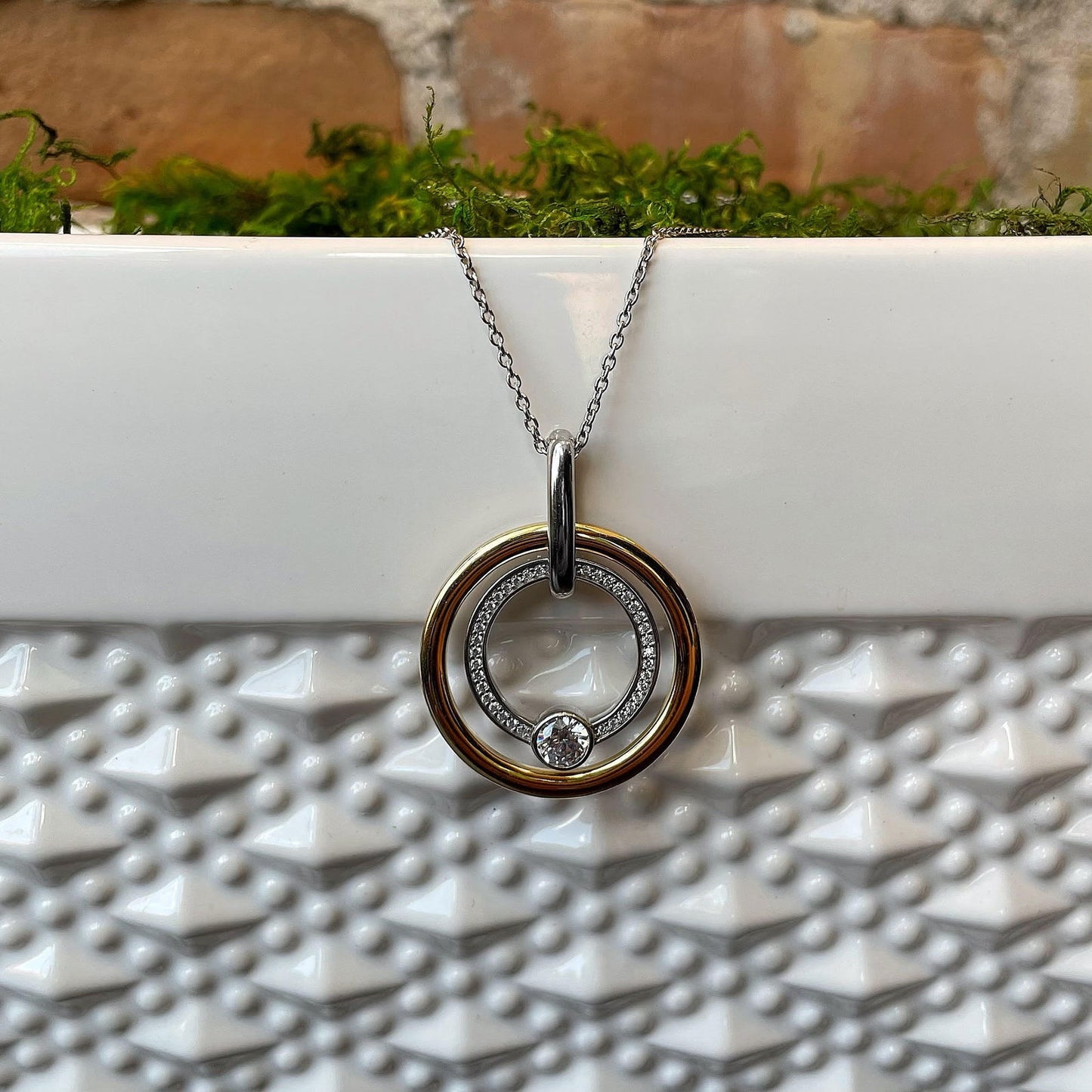 Photo of Cubic Zirconia Double Circle Pendant in a decorative scene, designed by , available at Plumb Gold & Plumb Silver