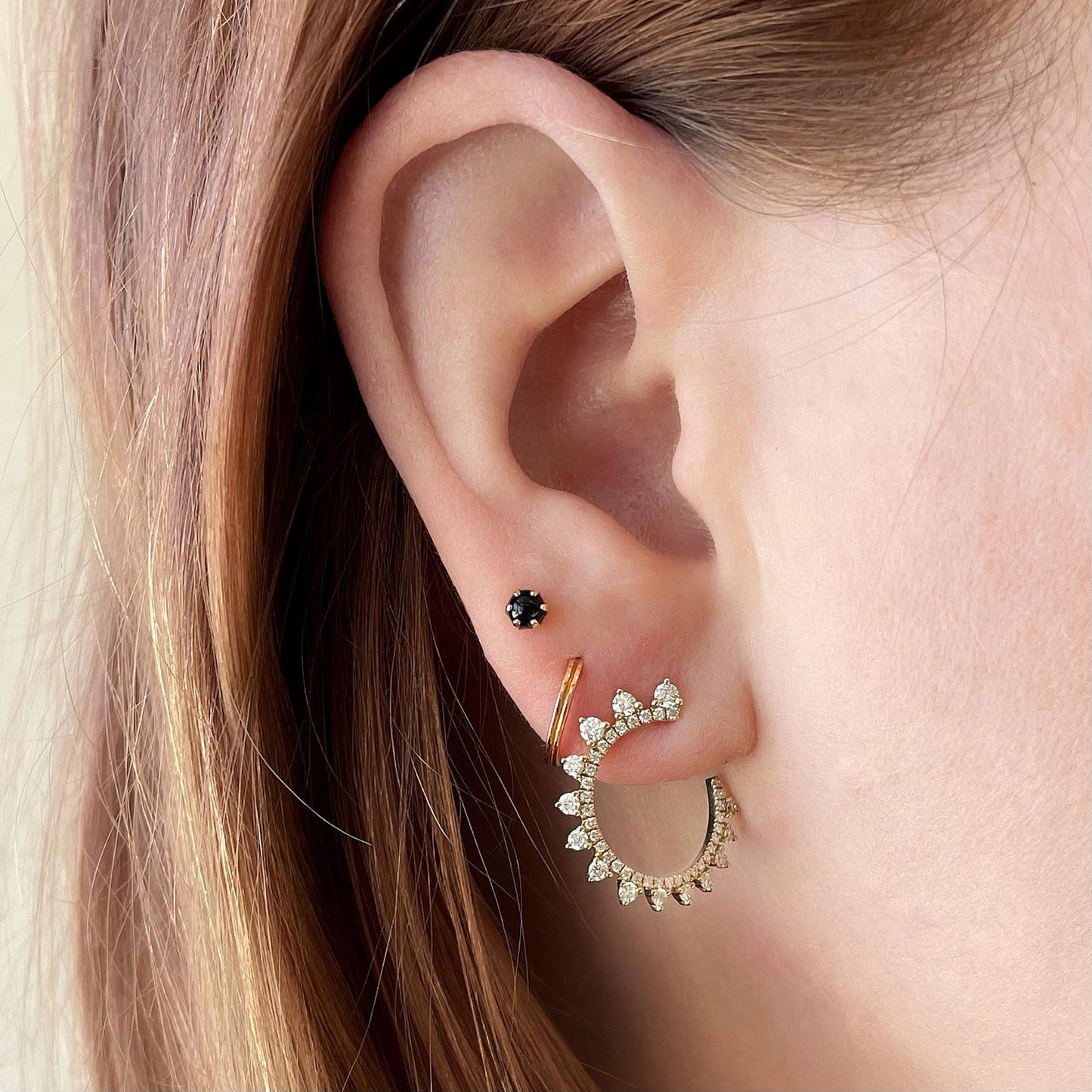 Photo of Curved Diamond Sunburst Wrap Around Earrings in a decorative scene, designed by , available at Plumb Gold & Plumb Silver