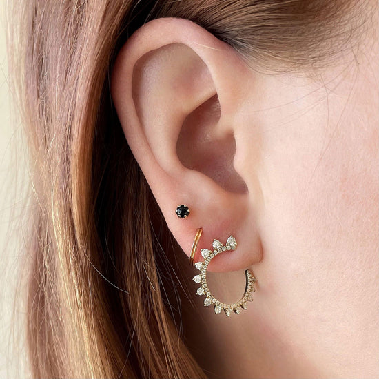 Photo of Curved Diamond Sunburst Wrap Around Earrings in a decorative scene, designed by , available at Plumb Gold & Plumb Silver