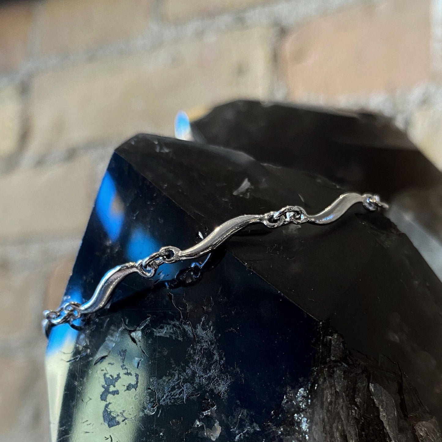 Photo of Curvy Link Bracelet in a decorative scene, designed by , available at Plumb Gold & Plumb Silver