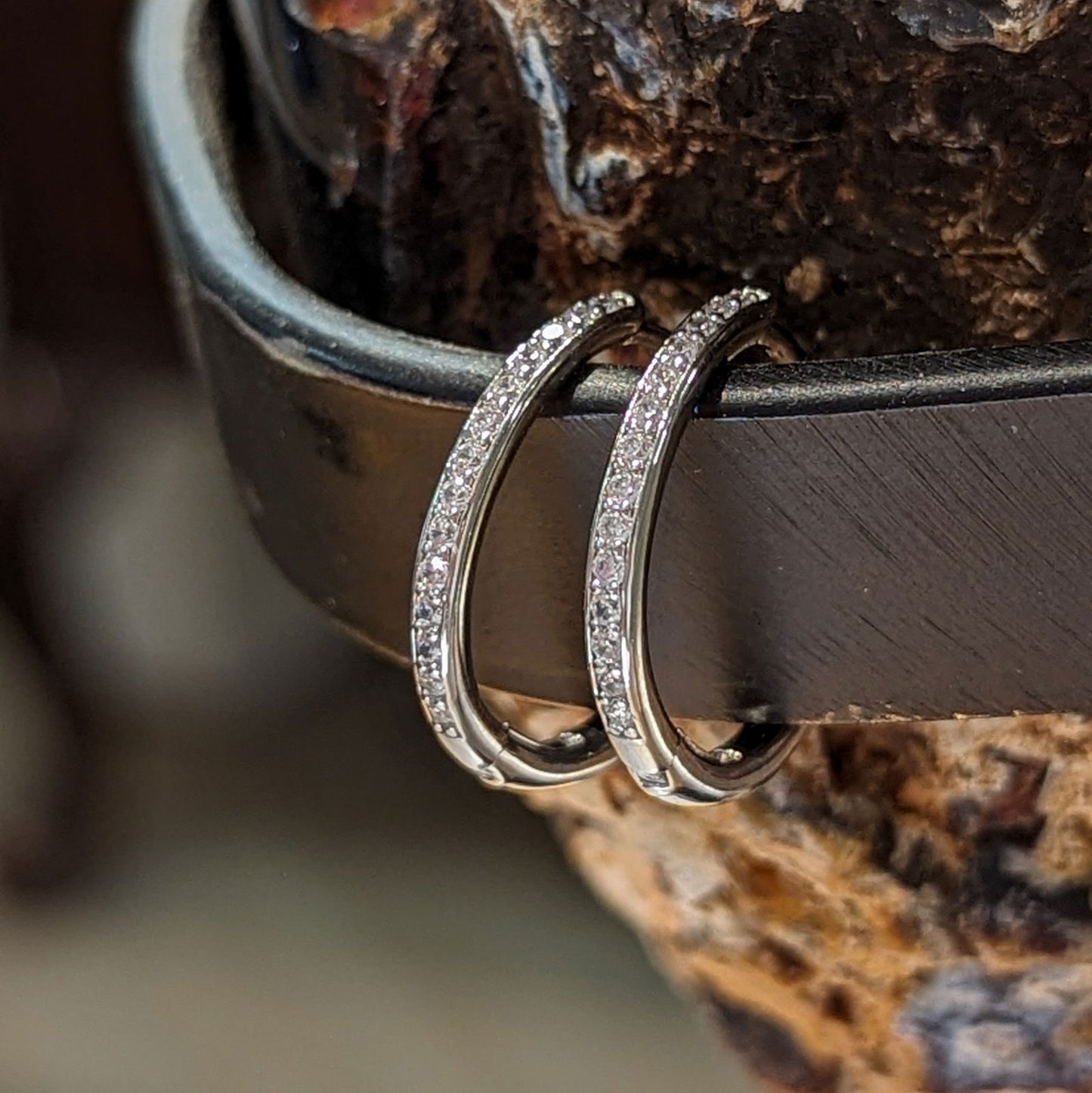 Photo of Cz Huggie Hoops in a decorative scene, designed by , available at Plumb Gold & Plumb Silver