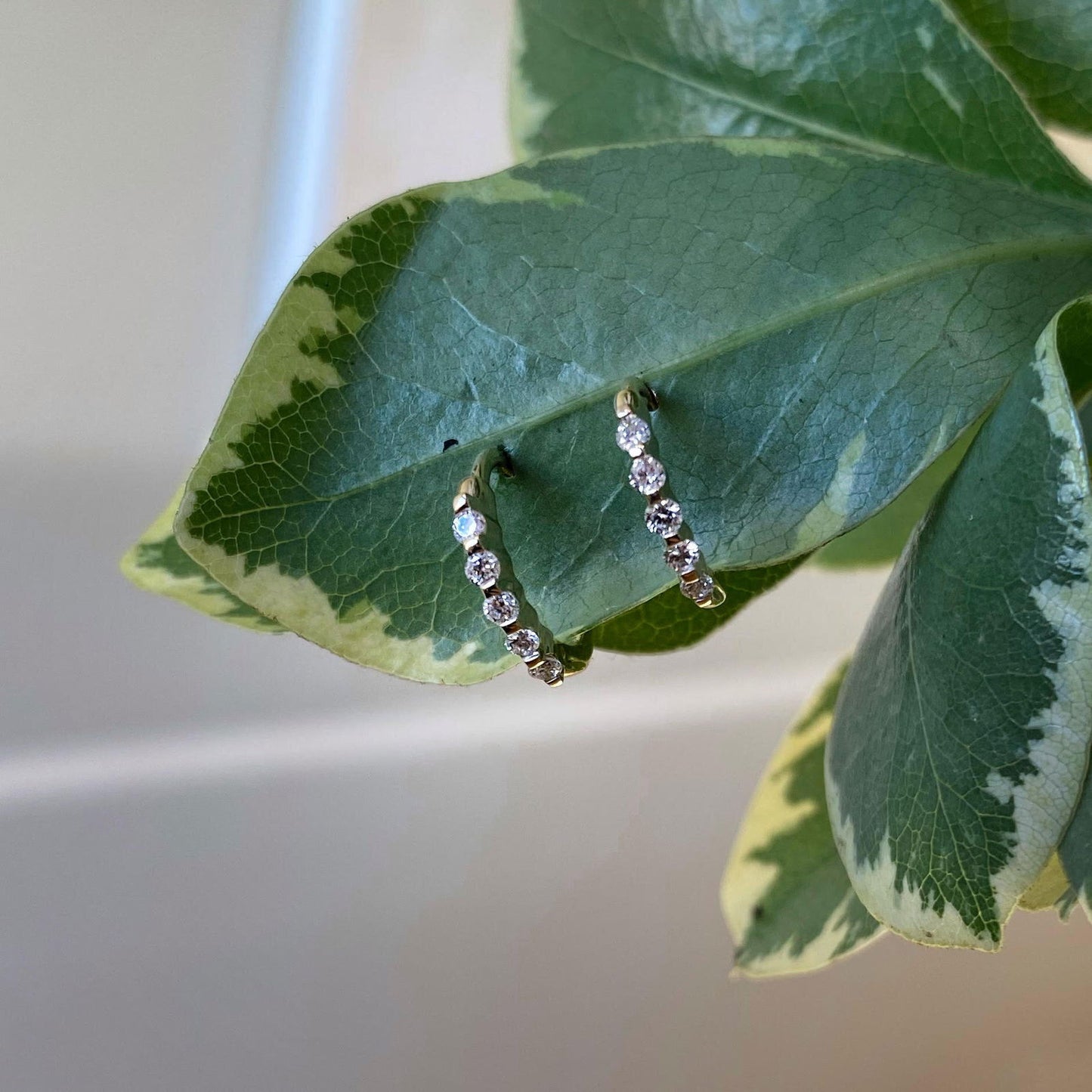Photo of Diamond Hinged Hoop Earrings in a decorative scene, designed by , available at Plumb Gold & Plumb Silver