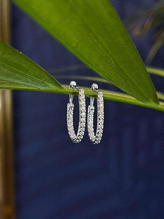 Photo of Diamond Inside-Out Oval Hoops in a decorative scene, designed by , available at Plumb Gold & Plumb Silver