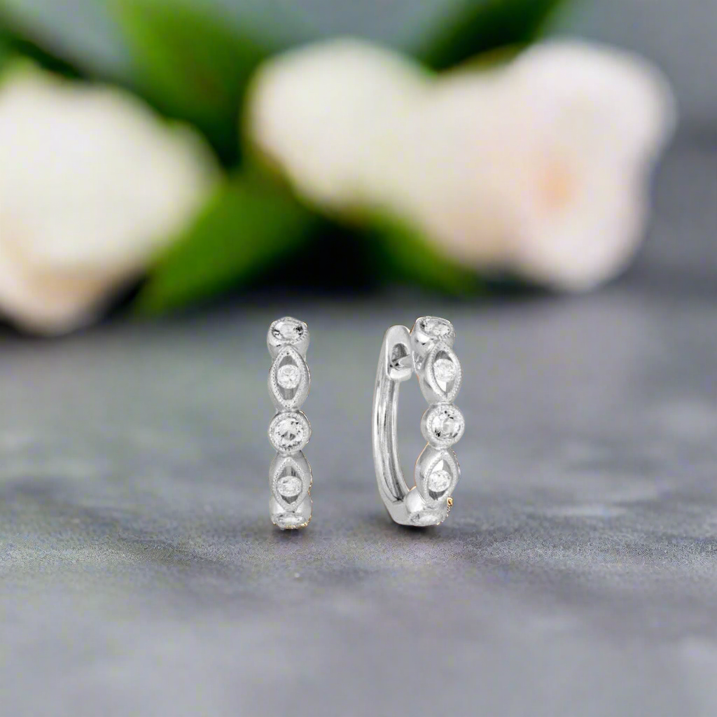 Photo of Diamond Milgrain Huggie Hoops in a decorative scene, designed by , available at Plumb Gold & Plumb Silver