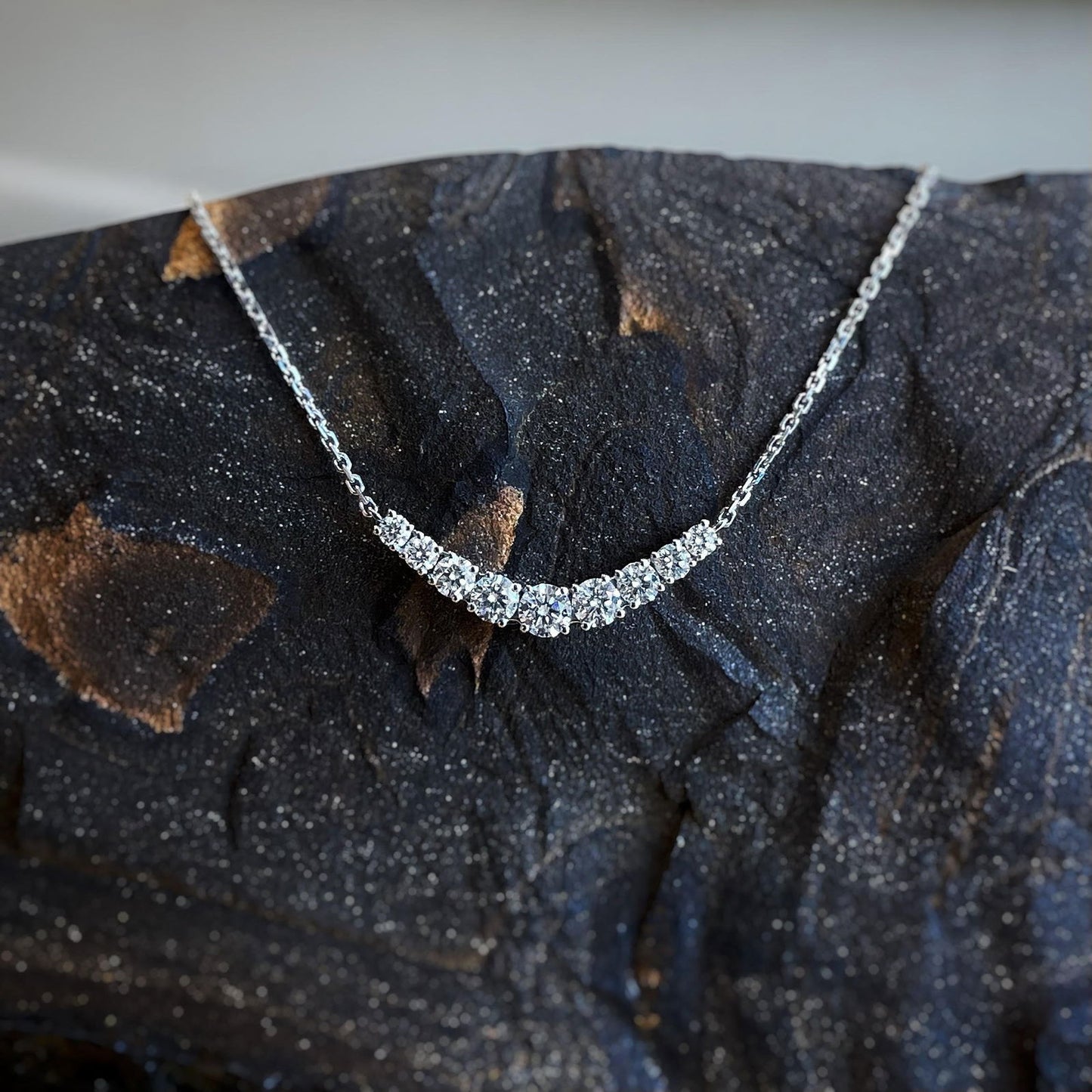 Photo of Diamond Smile Necklace in a decorative scene, designed by , available at Plumb Gold & Plumb Silver