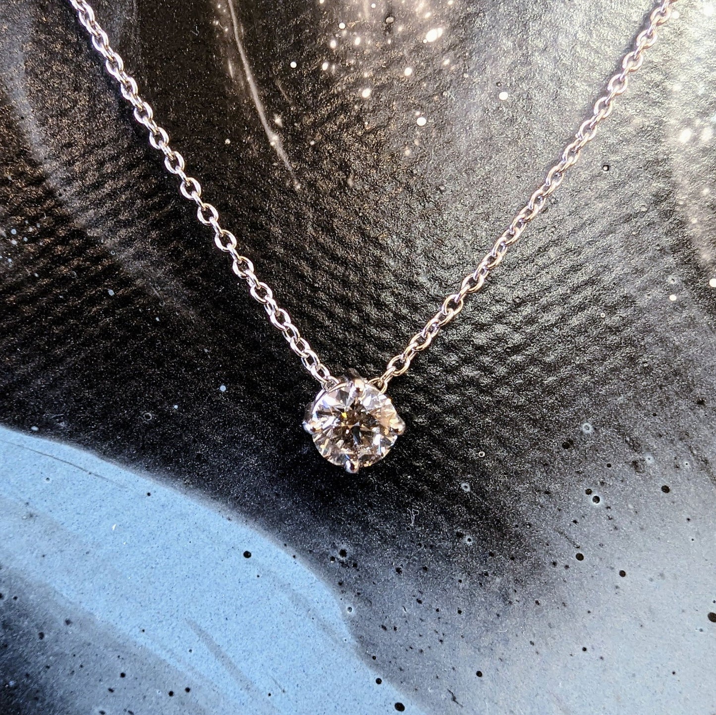 Photo of Diamond Solitaire Necklace in a decorative scene, designed by , available at Plumb Gold & Plumb Silver