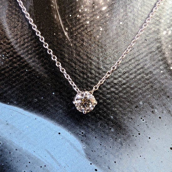 Photo of Diamond Solitaire Necklace in a decorative scene, designed by , available at Plumb Gold & Plumb Silver
