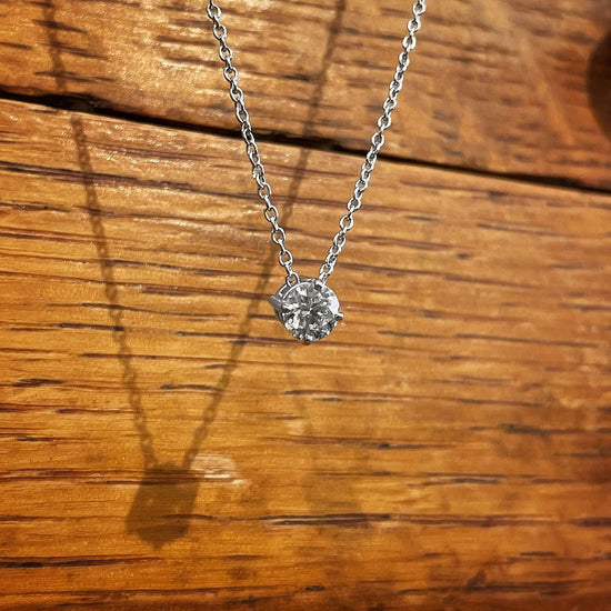 Photo of Diamond Solitaire Necklace in a decorative scene, designed by , available at Plumb Gold & Plumb Silver