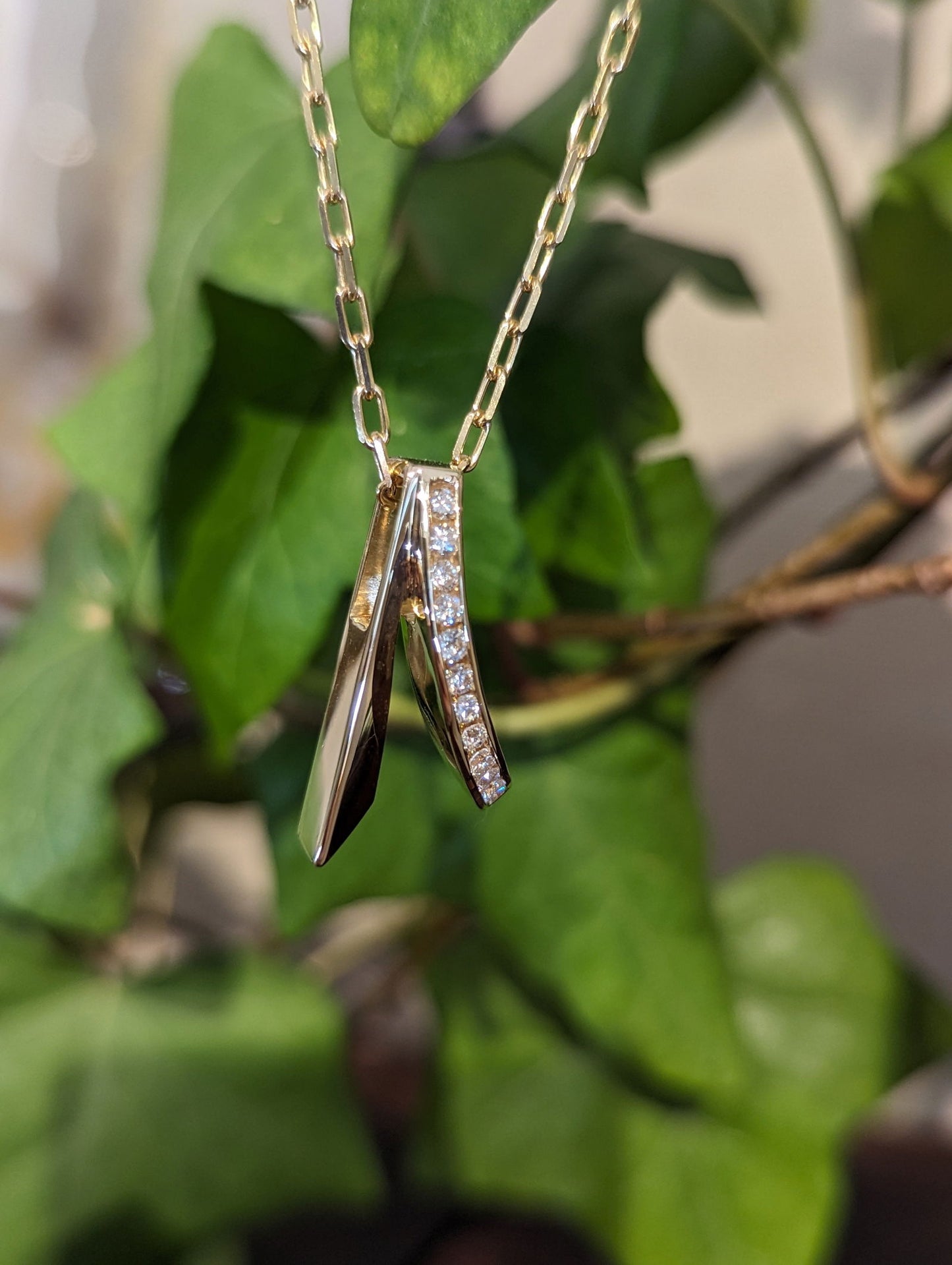 Photo of Diamond Swoop Pendant in a decorative scene, designed by , available at Plumb Gold & Plumb Silver