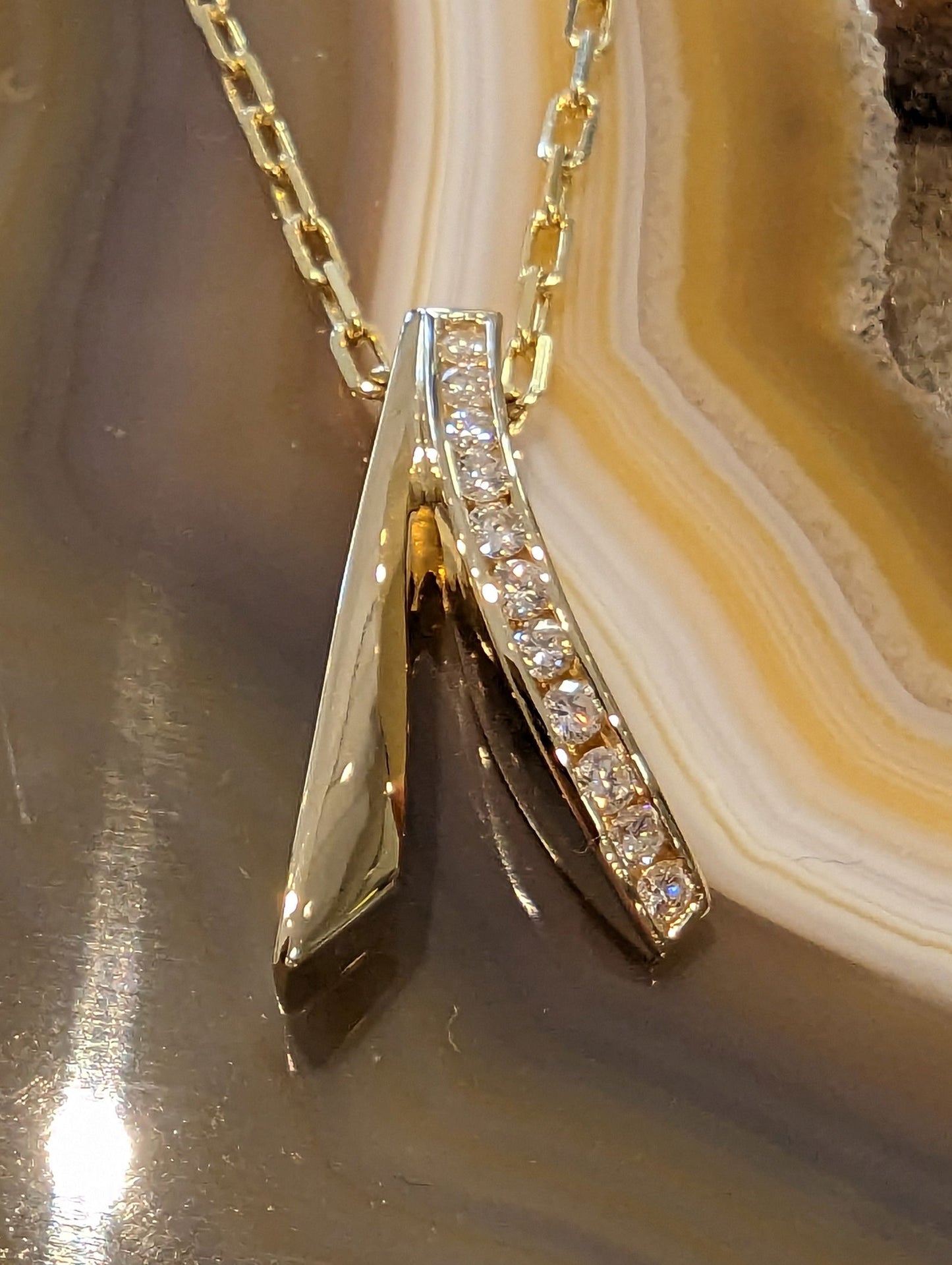 Photo of Diamond Swoop Pendant in a decorative scene, designed by , available at Plumb Gold & Plumb Silver