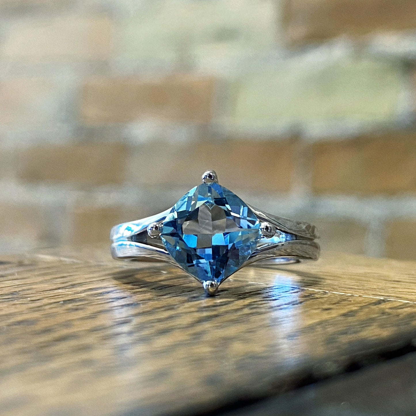 Photo of Double "V" Ring with Blue Topaz in a decorative scene, designed by , available at Plumb Gold & Plumb Silver