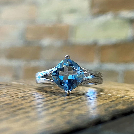 Photo of Double "V" Ring with Blue Topaz in a decorative scene, designed by , available at Plumb Gold & Plumb Silver