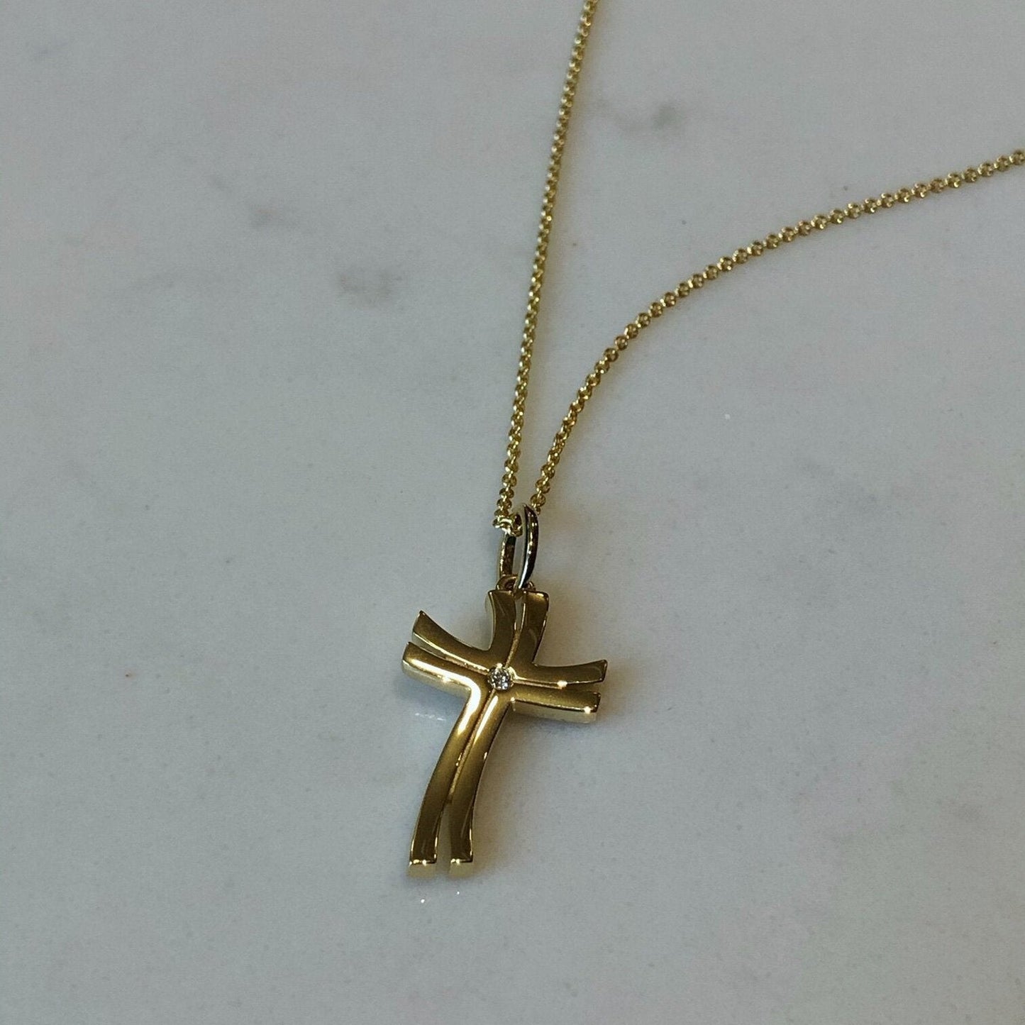 Photo of Double Wave Cross Pendant in a decorative scene, designed by , available at Plumb Gold & Plumb Silver