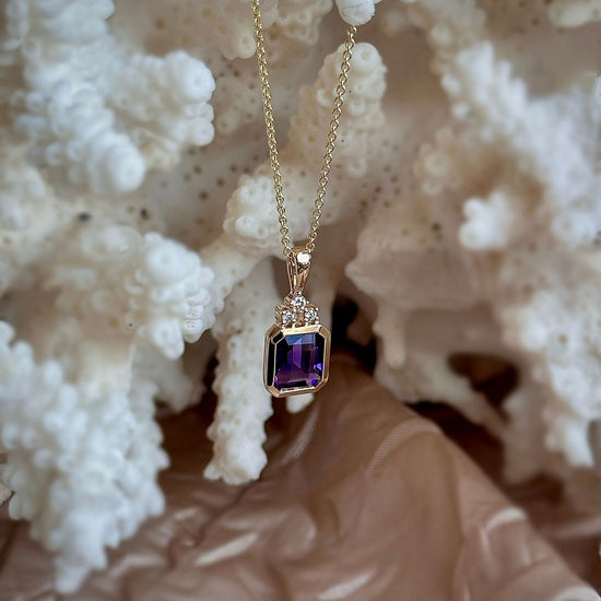 Photo of Emerald Cut Amethyst and Diamond Necklace in a decorative scene, designed by , available at Plumb Gold & Plumb Silver