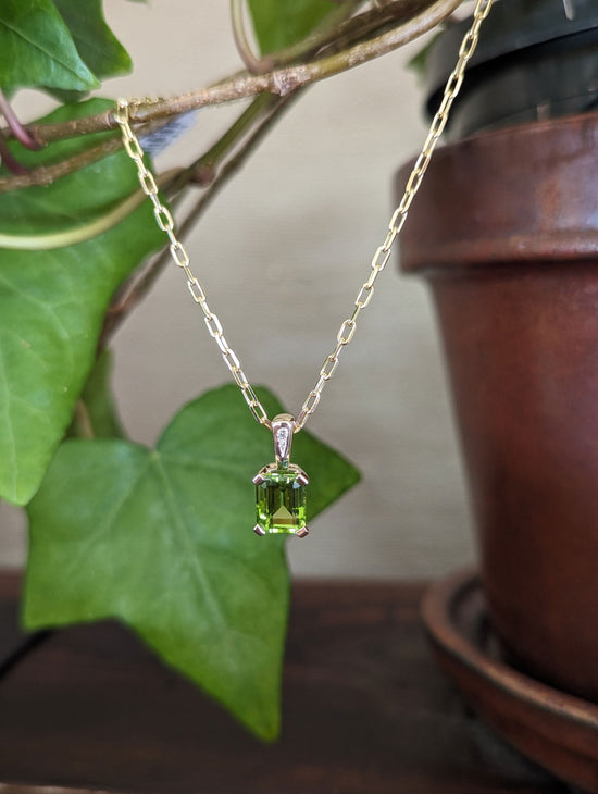 Photo of Emerald Cut Peridot Pendant in a decorative scene, designed by , available at Plumb Gold & Plumb Silver
